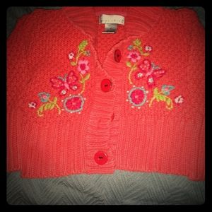 Coral colored knit sweater with floral embellishme